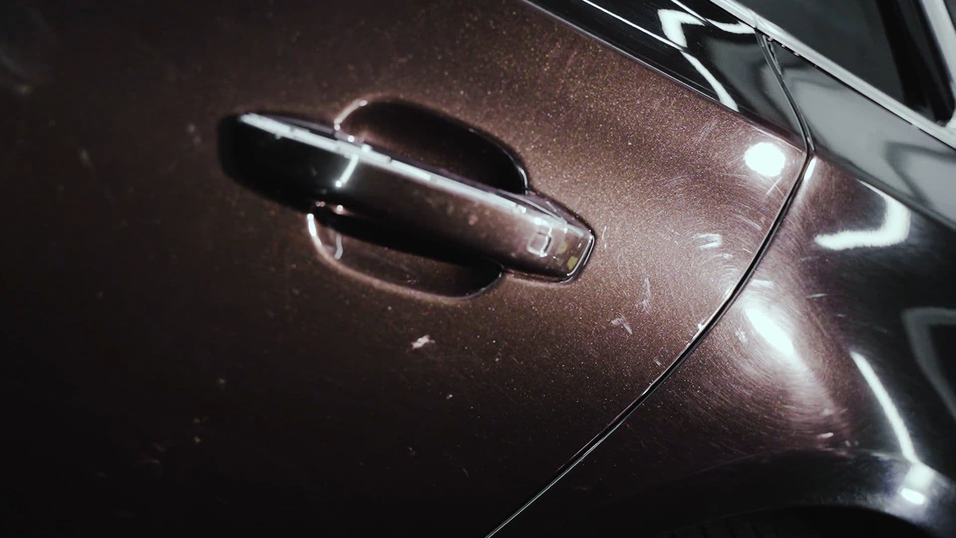 Maçaneta de um carro em close, com marcas na pintura